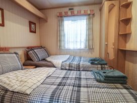 A bedroom with two single beds with checked bedding a window with curtains and a wardrobe at Willebby in South Chard