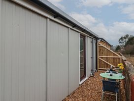 An outdoor area with a green table and two chairs beside a grey building at Bobby's Lodge in South Chard