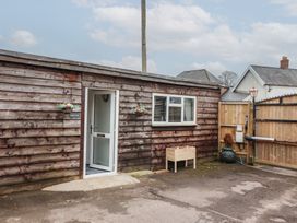 A wooden building with an open door and a window next to a fenced yard at Bobbys Lodge in South Chard