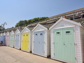 A row of small beach huts with pastel colored doors along a walkway with people sitting on benches above Bobby's Lodge in South Chard
