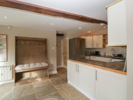 A kitchen with cabinets and a bench at Stable Cottage in Broadway