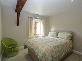 A bedroom with a bed and a chair at Stable Cottage in Broadway