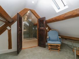 A bathroom with a shower and armchair at Stable Cottage in Broadway