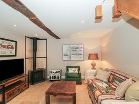 A living room with a couch, coffee table, and fireplace at Stable Cottage in Saintbury near Broadway