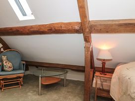 A bedroom with a chair and table at Stable Cottage in Saintbury near Broadway