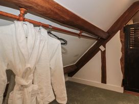 A storage room with a robe on a hanger at Stable Cottage in Saintbury near Broadway