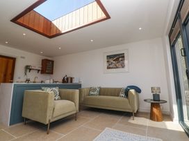 A living area with beige armchairs a sofa and a side table under a skylight at Little Victory in Pendeen