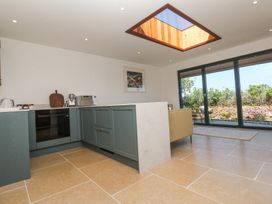 A kitchen with blue cabinets a built in oven and microwave and large windows with view of garden at Little Victory in Pendeen