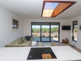 A living room with two sofas a wall-mounted television and large sliding glass doors at Little Victory in Pendeen