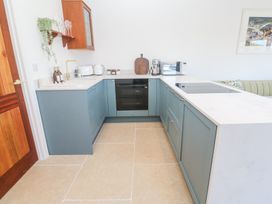 A kitchen with blue lower cabinets white countertops an oven microwave and coffee machine at Little Victory in Pendeen