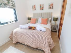 A bedroom with a double bed with cushions bedside tables and lamps a window and a tray with orange juice and fruit at Little Victory in Pendeen