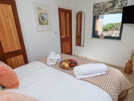 A bedroom with a bed topped with towels and a tray of food a wall mirror two wooden doors and a window with a floral blind at Little Victory in Pendeen