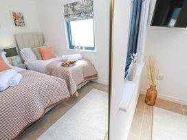 A bedroom with two single beds with checkered bedspreads and a TV on the wall at Little Victory in Pendeen