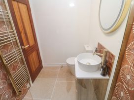 A bathroom with a wooden door a toilet a round sink with a faucet a mirror and a towel rack at Little Victory in Pendeen