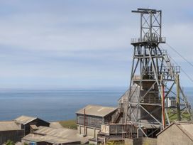 A coastal view of industrial mining buildings and a metal mining framework at Little Victory in Pendeen
