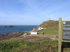 A coastal landscape with rocky shore a few white buildings and a hill with a monument at Cape Cornwall
