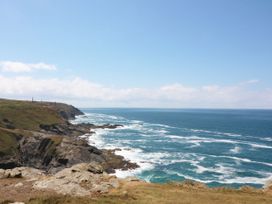 A rocky coastline with waves crashing and a clear blue sky at Little Victory in Pendeen