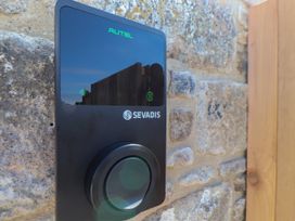 A black Sevadis device mounted on a stone wall near a wooden door in Little Victory Pendeen