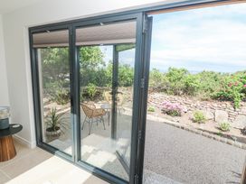 A patio with two wicker chairs and a small round table outside glass folding doors at Little Victory in Pendeen
