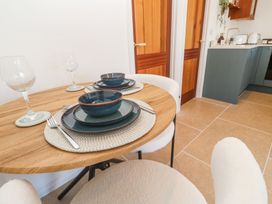 A round wooden dining table set with plates bowls cutlery and wine glasses in a kitchen at Little Victory in Pendeen
