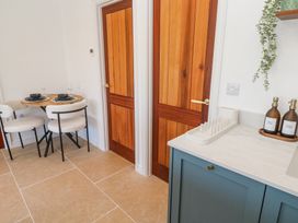 A kitchen area with blue cabinets a dish drying rack soap dispensers and a small dining table with two chairs at Little Victory in Pendeen