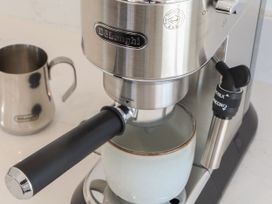 An espresso machine with a coffee cup and milk jug at Little Victory in Pendeen