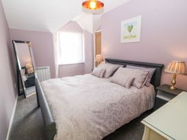A bedroom with a double bed linens bedside tables lamps a tall mirror and a window at Medical Hall in Cemaes Bay