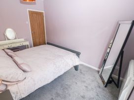 A bedroom with a bed, a dressing table with a mirror, a full-length mirror, a wooden door, and a heater at Medical Hall in Cemaes Bay
