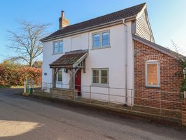 A two-story house with white walls red front door and brick extension on a street at Curlew Cottage North Curry near Taunton