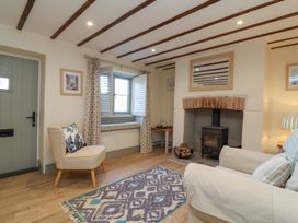 A living room with a stove fireplace wooden beams on ceiling and a patterned rug at Curlew Cottage North Curry near Taunton