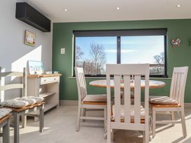 A dining area with table and chairs near a window with green walls at Curlew Cottage in North Curry near Taunton