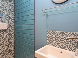 A bathroom with a white sink blue subway tiles and patterned tiles at Curlew Cottage in North Curry near Taunton