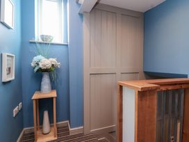 A small corner with blue walls a wooden stand holding vases and a staircase railing in Curlew Cottage North Curry near Taunton