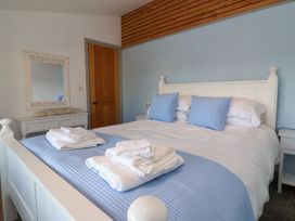 A bedroom with a white bed with blue pillows and blue bedspread with towels on it a wooden door a white dresser with a mirror
