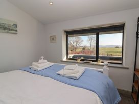 A bedroom with a bed covered with white and blue linens and folded towels on top by a window with a view of trees and fields at Curlew Cottage in North Curry near Taunton