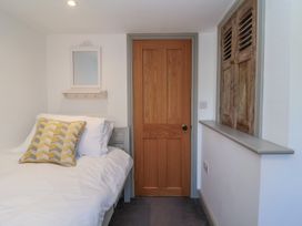 A bedroom with a bed a wooden door a wall mirror and wooden shutter at Curlew Cottage in North Curry near Taunton