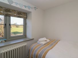 A bedroom with a window overlooking a field a bed with folded towels on a striped blanket at Curlew Cottage in North Curry near Taunton