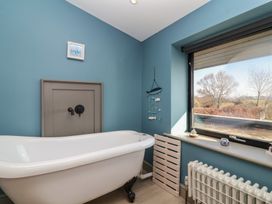 A bathroom with a freestanding bathtub a window and a radiator at Curlew Cottage in North Curry near Taunton