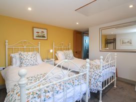 A bedroom with two single beds white metal frames floral bedding and a yellow accent wall at Curlew Cottage in North Curry near Taunton