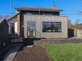 A wooden house with large windows a garden shed and a grass lawn at Curlew Cottage North Curry near Taunton