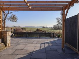 A paved patio with a wooden pergola and a view of fields at Curlew Cottage in North Curry near Taunton