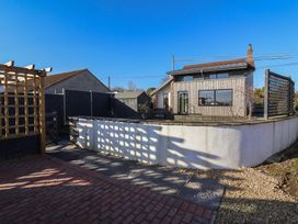 An exterior view of a modern house with a wooden fence wall and paved and gravel ground at Curlew Cottage in North Curry near Taunton