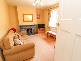 A living room with a sofa cushions fireplace television and a wooden coffee table at Maiden Moor in Grange near Keswick