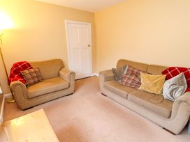 A living room with two beige sofas with cushions and red blankets and a wooden coffee table at Maiden Moor in Grange near Keswick
