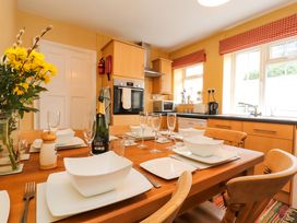A kitchen with a wooden dining table set with white dishes and glasses and yellow flowers on the table at Maiden Moor in Grange near Keswick