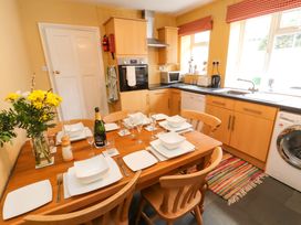 A kitchen with a dining table set with plates glasses and a bottle near cabinets and appliances at Maiden Moor in Grange near Keswick