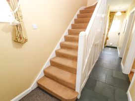 A hallway with carpeted stairs and a slate tile floor leading to a door at Maiden Moor in Grange near Keswick