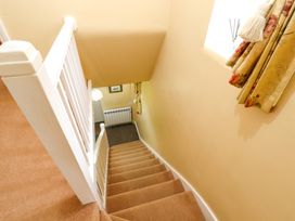 A carpeted staircase with white banister and yellow walls with floral curtains at Maiden Moor in Grange near Keswick