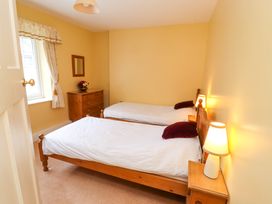 A bedroom with two single beds wooden furniture a window a chest of drawers and table lamps at Maiden Moor in Grange near Keswick