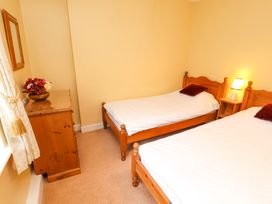 A bedroom with two single beds a wooden chest of drawers with flowers and a small bedside table with a lamp at Maiden Moor Grange near Keswick